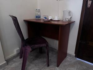 N Joy Inn في ترينكومالي: مكتب خشبي مع كرسي في الغرفة