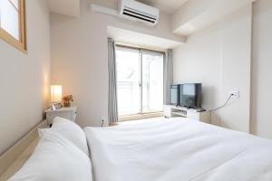 een witte slaapkamer met een bed en een televisie bij Rewitビル in Osaka