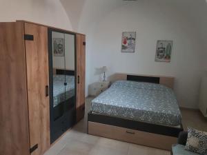 a bedroom with a bed and a wooden cabinet at Dimora Grecale in Cisternino