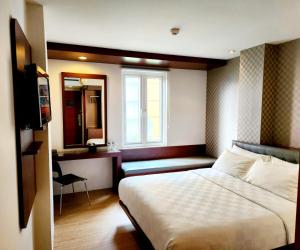 Habitación de hotel con cama y ventana en M Hotel, en Yakarta
