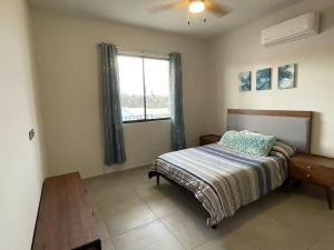 1 dormitorio con cama, mesa y ventana en Maralta Condominio con Vista al Mar, en Cabo San Lucas