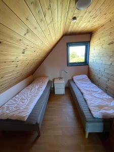 Habitación con 2 camas, techo de madera y ventana. en Nautnes Seaside Apartments A5 en Nautnes