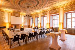 Habitación grande con mesas, sillas y pantalla de proyección en Sorell Hotel Rüden, en Schaffhausen