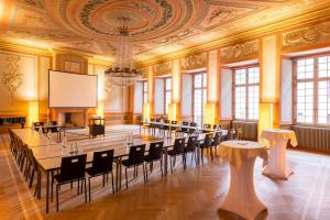 Sorell Hotel Rüden في شافهاوزن: غرفة كبيرة بها طاولات وكراسي وشاشة عرض