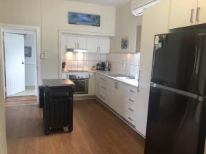 Una cocina con refrigerador negro y gabinetes blancos. en Pina Colada on the Beach - Beachfront - 2 Bedroom, en Mission Beach