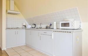 a kitchen with white cabinets and a microwave at Beautiful Apartment In Dagebll With Kitchen in Dagebüll