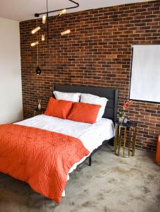 a bedroom with a brick wall and a bed with orange pillows at Moderno, cómodo y lindo departamento en Tijuana BC in Tijuana