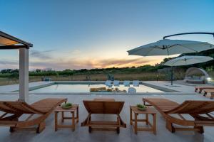 eine Terrasse mit Stühlen und Sonnenschirmen sowie einem Pool in der Unterkunft Villa Slatina near Zrce beach in Novalja