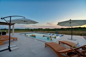 einen Pool mit 2 Stühlen und einem Sonnenschirm in der Unterkunft Villa Slatina near Zrce beach in Novalja