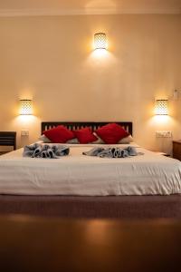 ein Schlafzimmer mit einem großen weißen Bett mit roten Kissen in der Unterkunft Sea Breeze Village, Baga Goa in Calangute
