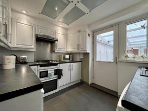 cocina con armarios blancos y fogones en Maria's House in East London, en Dagenham