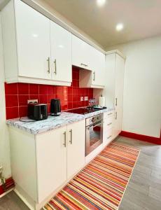 una cocina con armarios blancos y azulejos rojos en Opal Apartment en Leicester