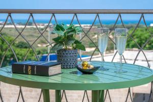 un tavolo con due bicchieri e un libro e una pianta di Mina's luxury suite - panoramic sea view- קיסריה a Caesarea