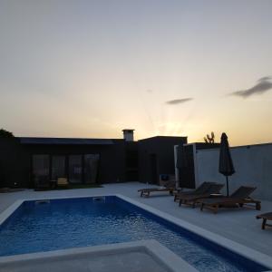 a swimming pool with chairs and a sunset in the background at Villa Dalmatia in Slivnica