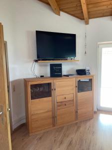 a wooden entertainment center with a flat screen tv on a wall at Oyer Ferienhaus in Oy-Mittelberg