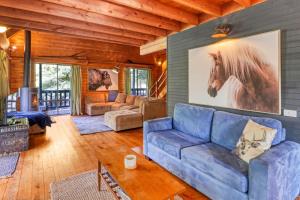 een woonkamer met een blauwe bank en een paardenfoto aan de muur bij The Bower in Merrijig