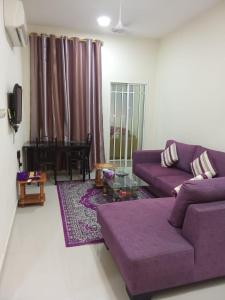 a living room with a purple couch and a table at Argaan Apartment in Salalah