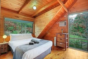 een slaapkamer met een bed in een houten hut bij The Bower in Merrijig