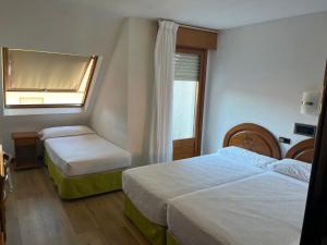 Habitación de hotel con 2 camas y ventana en Hotel Pelayo Isla, en Isla