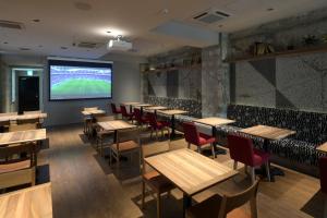 a restaurant with tables and chairs and a projection screen at HOTEL MYSTAYS Okayama in Okayama