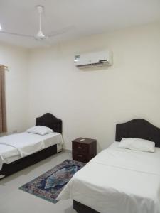 a room with two beds and a heater on the wall at Argaan Apartment in Salalah