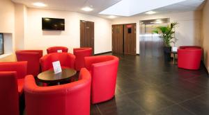 una sala de espera con sillas rojas y una mesa en Hotel Eurocentre 2* Toulouse Nord, en Castelnau-dʼEstrétefonds