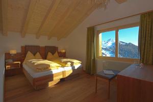 ein Schlafzimmer mit einem Bett und einem großen Fenster in der Unterkunft Hotel Waldhaus in Bettmeralp