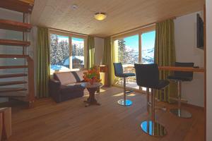 uma sala de estar com um sofá, uma mesa e cadeiras em Hotel Waldhaus em Bettmeralp