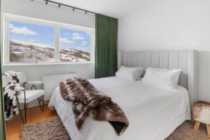 a bedroom with a large white bed with a large window at MarkII 4 West in Mount Buller