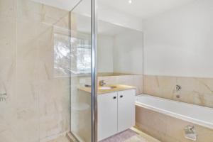 a bathroom with a shower and a sink and a tub at MarkII 4 West in Mount Buller