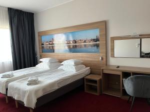a hotel room with two beds and a large painting on the wall at Hotel Meeting in Toruń