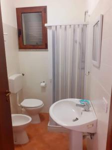 a white bathroom with a toilet and a sink at Hotel Bena e Traes in Laerru