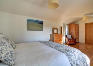 a bedroom with a large bed and a chair at The Granary Trevisquite in Saint Tudy
