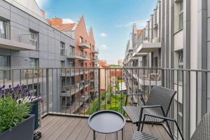 um apartamento varanda com cadeiras e uma mesa em Grano Residence - Pool, Sauna, SPA & Parking by Downtown Apartments em Gdansk