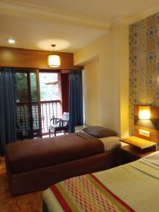 a hotel room with two beds and a balcony at Sea Breeze Inn, Calangute Goa in Calangute