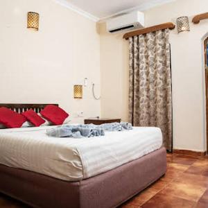 a bedroom with a large bed with red pillows at Sea Breeze Inn, Calangute Goa in Calangute
