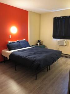 a bedroom with a bed and a red wall at The Canterbury Inn of Downtown Invermere in Invermere