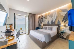 Habitación de hotel con cama, escritorio y ventana en Naxos Marina Bay en Giardini Naxos