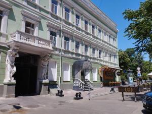 zielony i biały budynek z pomnikiem przed nim w obiekcie In the heart of Odessa w Odessie