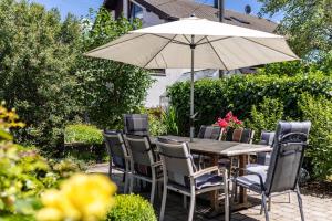 une table en bois avec des chaises et un parasol dans l'établissement Alb Rose Ferienwohnung, à Sonnenbühl