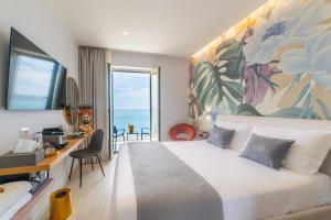 een slaapkamer met een groot bed, een bureau en een raam bij Naxos Marina Bay in Giardini Naxos