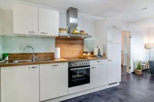 uma cozinha com armários brancos, um lavatório e um forno em Fewo-Keinath em Winterlingen
