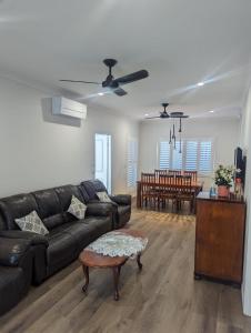 ein Wohnzimmer mit einem schwarzen Ledersofa und einem Tisch in der Unterkunft Immaculate 2-Beds Entire House Chermside Brisbane in Brisbane