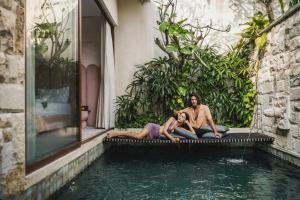 two people sitting on the edge of a pool of water at La Vie Villa Seminyak by Ini Vie Hospitality in Legian