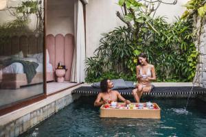 two men sitting in the water in a swimming pool at La Vie Villa Seminyak by Ini Vie Hospitality in Legian