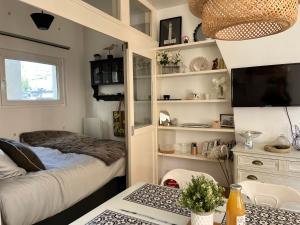 Habitación pequeña con cama, escritorio y TV. en Coup de Cœur, en Trouville-sur-Mer