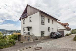 une maison blanche avec une voiture garée devant elle dans l'établissement See- Panorama, à Gaienhofen