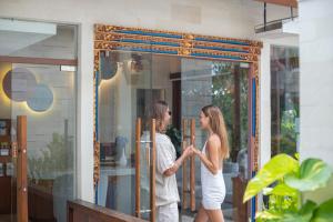 Un hombre y una mujer de pie frente a una puerta de cristal. en La Vie Villa Seminyak by Ini Vie Hospitality, en Legian