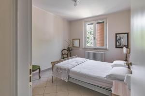 a white bedroom with a bed and a window at A due passi da Borgo San Giuliano Apartment in Rimini