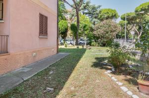 einen Hof neben einem rosa Gebäude mit Garten in der Unterkunft A due passi da Borgo San Giuliano Apartment in Rimini
